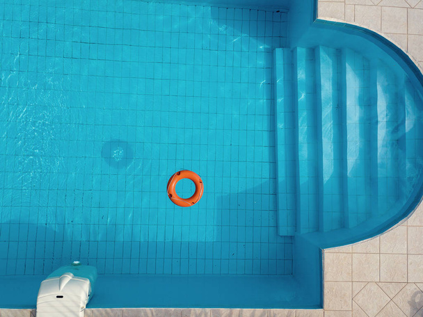 Апельсиновый спасательный круг в бассейне летом
 - Фото, изображение