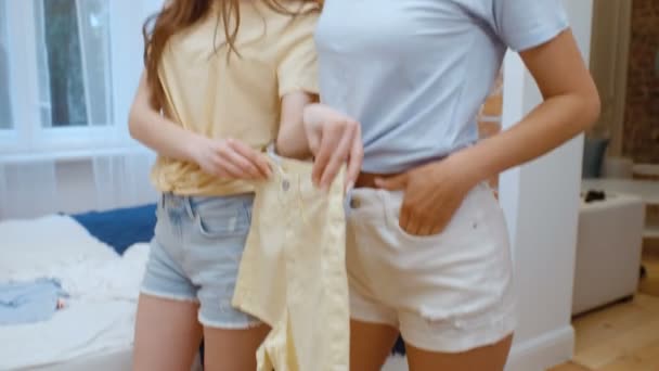 Two cheerful pretty young women trying on clothes. - Záběry, video