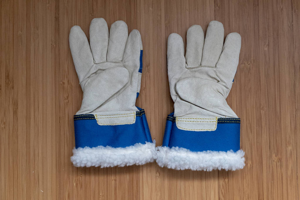 twee tuin handschoenen voor kinderen op hout met blauwe tailleband - Foto, afbeelding