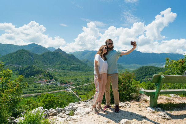 couple taking selfie from a hill overlooking the mountains - Foto, Imagen