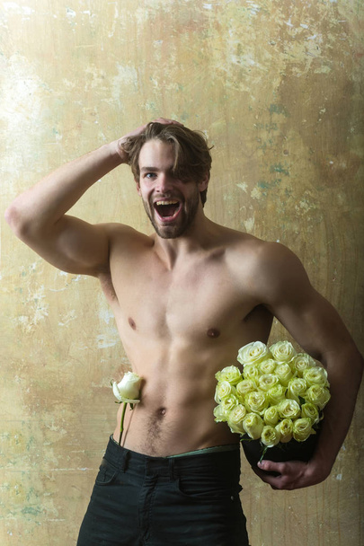 Beyaz çiçekli mutlu seksi adam. Çiçek gülleri tutan sevimli maço adam. Mutlu romantik koca gül çiçek tutan ve kutlamak için hazır. Aşk erkek arka plan - Fotoğraf, Görsel