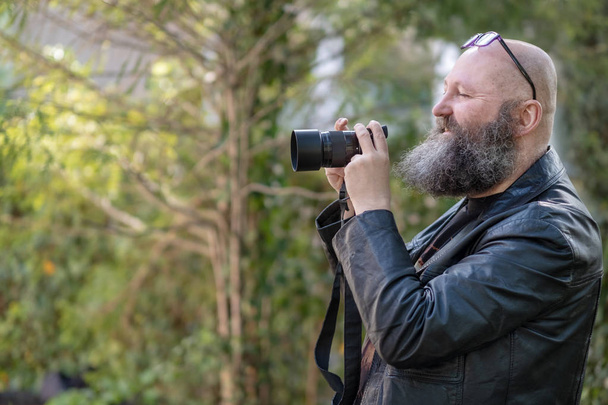 artista loco idiosincrásico con barba, sostiene una cámara de sistema digital
 - Foto, Imagen