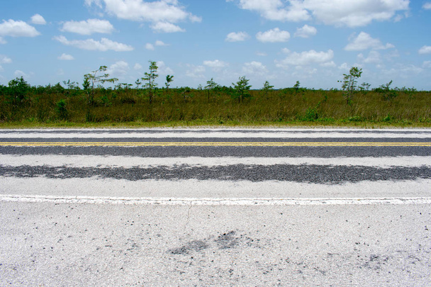 Estrada de asfalto afiada com campo de grama verde
 - Foto, Imagem