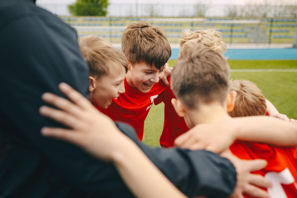 Un grupo de chicos felices haciendo grupos deportivos. Sonriendo niños de pie junto con el entrenador
 - Foto, Imagen