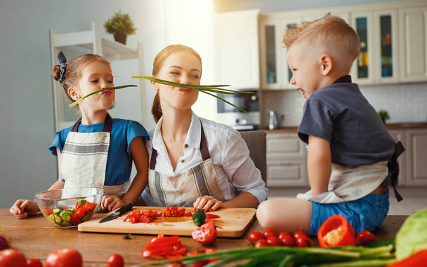 mother with children preparing vegetable salad  - Photo, Image