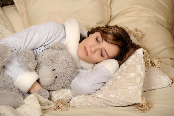 A woman sleeps with a teddy bear - Фото, зображення