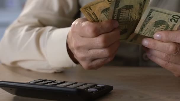 Senior man holding dollars, calculating incomes and expenses, home budget - Felvétel, videó