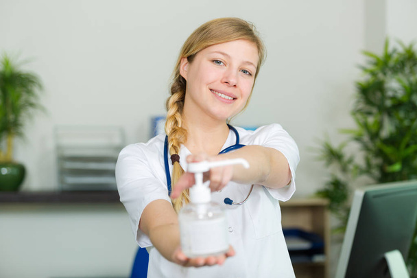 female nurse handing hand sanitizer - Фото, зображення