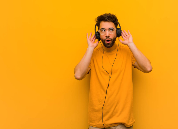 Νεαρός που ακούει μουσική προσπαθεί να ακούσει ένα κουτσομπολιό - Φωτογραφία, εικόνα