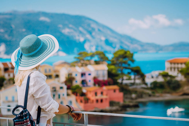 Tourist blond women with sun hat in cute colorful small Assos village. Kefalonia, Greece - Photo, Image