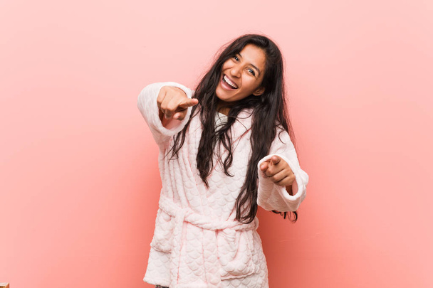Young indian woman wearing pajama cheerful smiles pointing to front. - Photo, Image