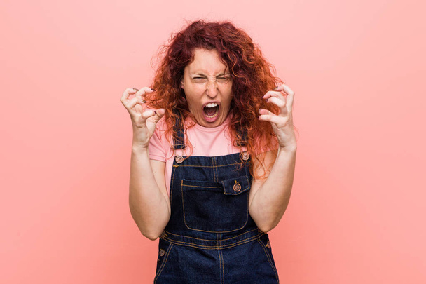Young pretty ginger redhead woman wearing a jeans dungaree screaming with rage. - Fotoğraf, Görsel