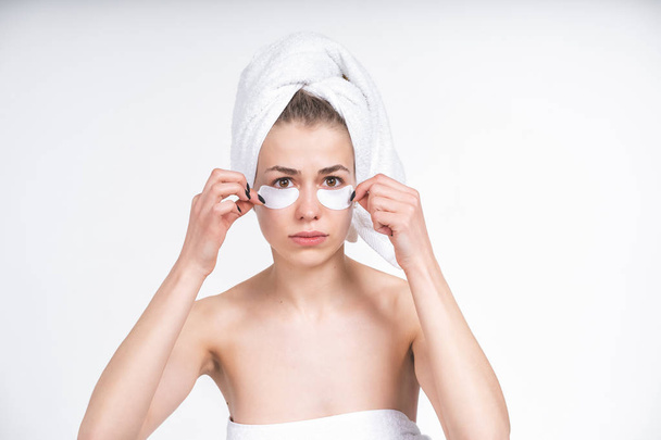 young white girl peels off patches for eyes. Upset. Facial, skin care. Beauty treatments - 写真・画像