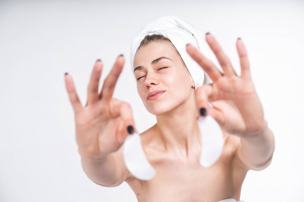 young naked girl in a towel shows patches for the eyes. Laughs happily. Happy Portrait on a blank background. Facial treatment. Skin care. - Foto, Imagem