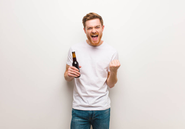 Young redhead man. Holding a beer. - Фото, зображення