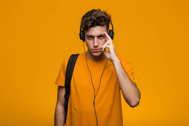 Nuori cool opiskelija mies kuuntelee musiikkia kuulokkeet yrittää kuunnella juoruja
. - Valokuva, kuva