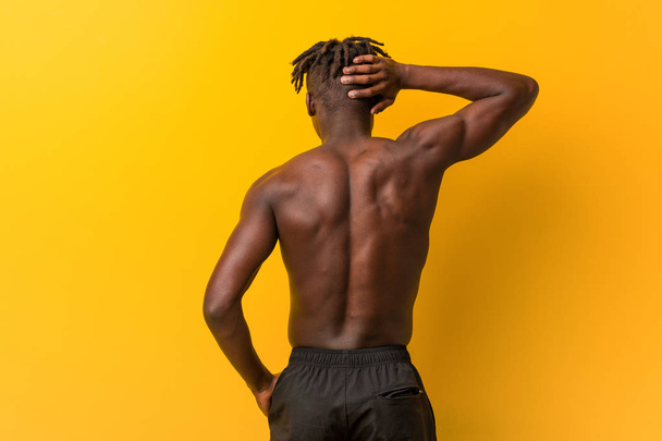Young black man shirtless wearing swimsuit from behind thinking about something. - Photo, Image