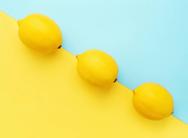 Limoni in fila su fondo giallo pastello e blu. Concetto estivo minimo Posa piatta
. - Foto, immagini