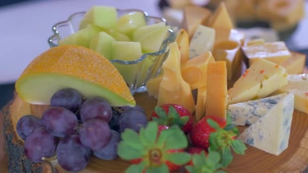 Different types of cheeses on a wooden board look very appetizing - Кадри, відео