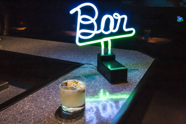 Alcoholic drink and bright neon writing bar on a balcony - Foto, Imagen