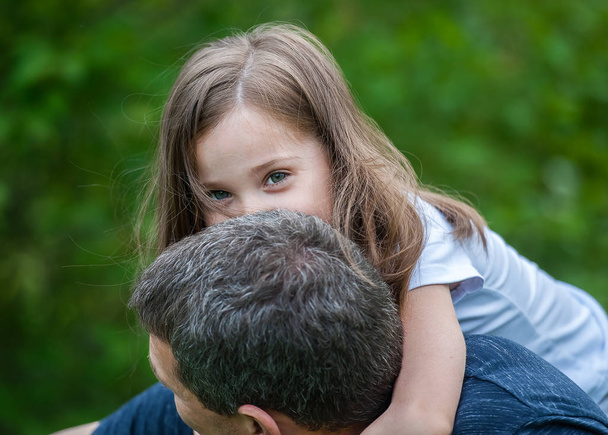 Portrait of cute little girl held in father's arms. Happy loving family. Father and his daughter child girl playing hugging. Cute baby and daddy. Concept of Father day. Family holiday and togetherness - Foto, Imagen
