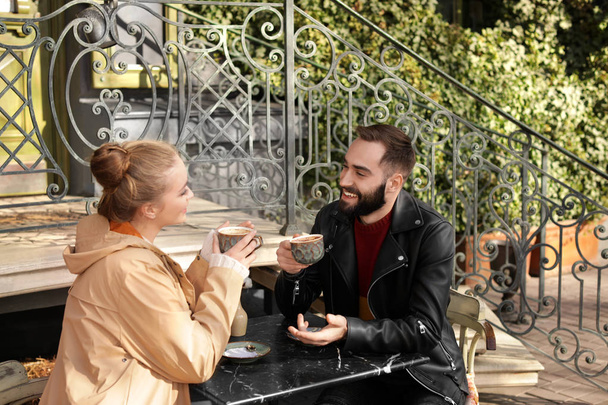 Lovely young couple enjoying tasty coffee at table outdoors - Valokuva, kuva