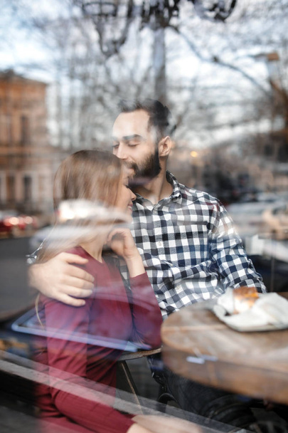 Lovely young couple spending time together in cafe, view from outdoors through window - Foto, Bild