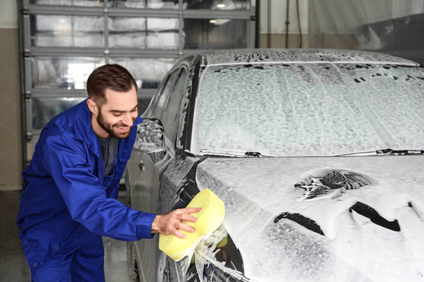 Worker cleaning automobile with sponge at professional car wash - 写真・画像