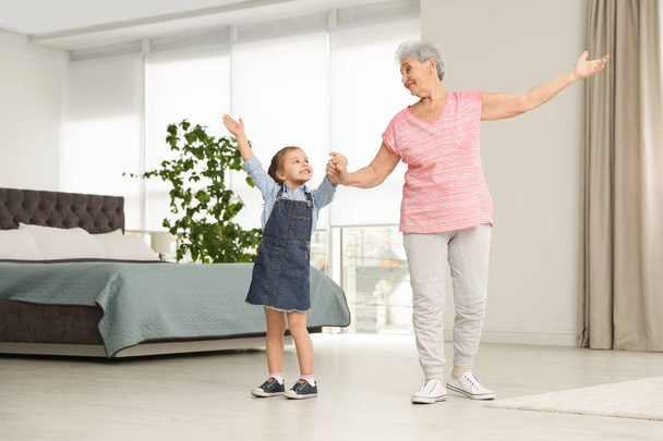 Cute girl and her grandmother dancing at home - Фото, зображення