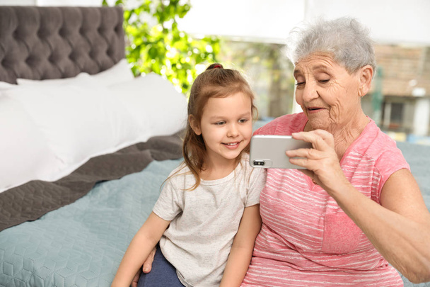 Cute girl and her grandmother taking selfie  at home - Fotoğraf, Görsel