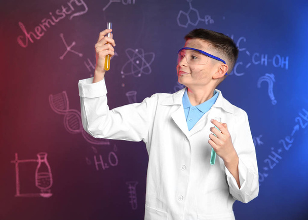 Schoolboy with test tubes against blackboard with written chemistry formulas - Foto, Imagen