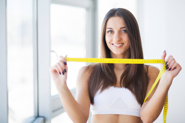 Diet. The girl taking measurements of her body, white background - Φωτογραφία, εικόνα