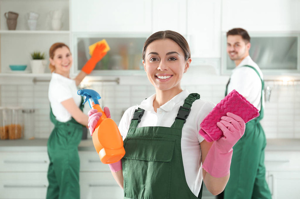 Portrait of young woman with sprayer and rag in kitchen. Cleaning service - Photo, Image