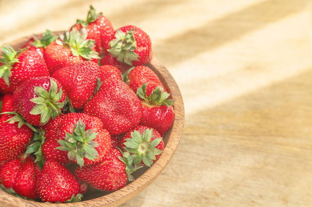 Φρέσκες όμορφες φράουλες σε ξύλινο μπολ με θέα. Φρούτα φράουλα σε ξύλινο χώρο αντιγραφής τραπέζι. - Φωτογραφία, εικόνα