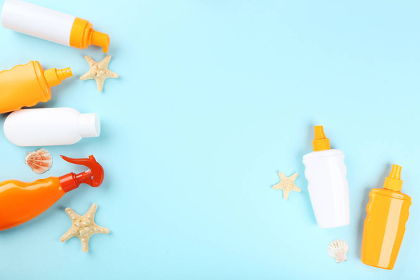 Sunscreen bottles with seashells and on blue background - Фото, изображение