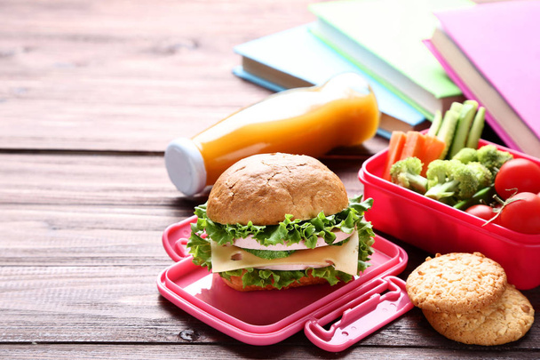 School lunch box with sandwich and bottle of juice on wooden tab - Foto, Bild