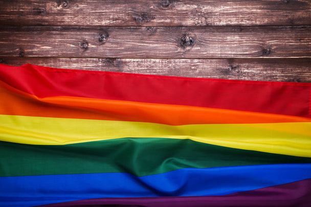 Rainbow flag on brown wooden table - Фото, изображение