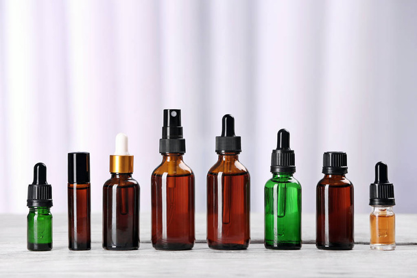 Bottles of essential oils on table against light background. Cosmetic products - Photo, Image