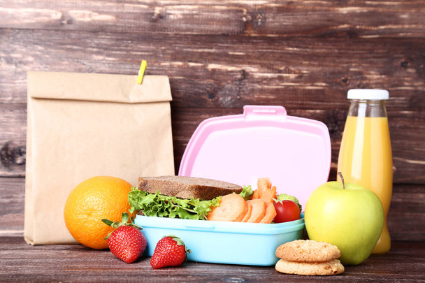 School lunch box with sandwich and fruits on wooden table - Photo, image
