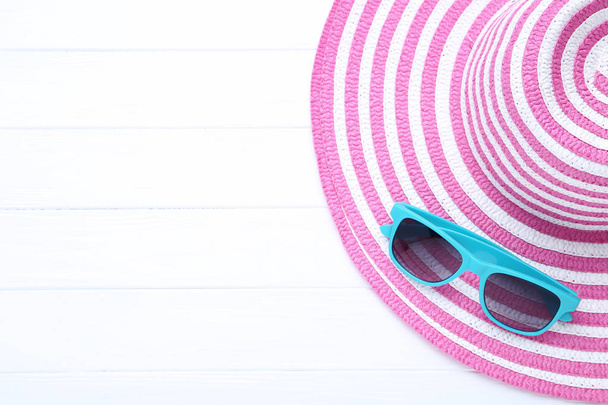 Beach hat with sunglasses on white wooden table - Φωτογραφία, εικόνα