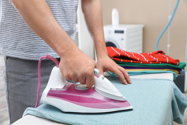 Man ironing clothes on board at home, closeup - Foto, imagen