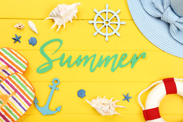 Word Summer with seashells and clothing on yellow wooden table - Фото, изображение