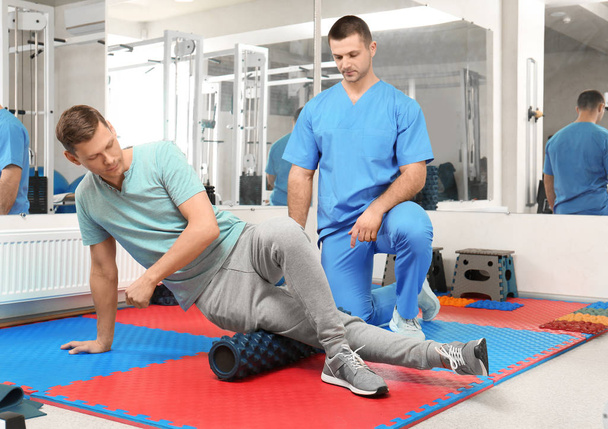 Patient exercising under physiotherapist supervision in rehabilitation center - Fotoğraf, Görsel
