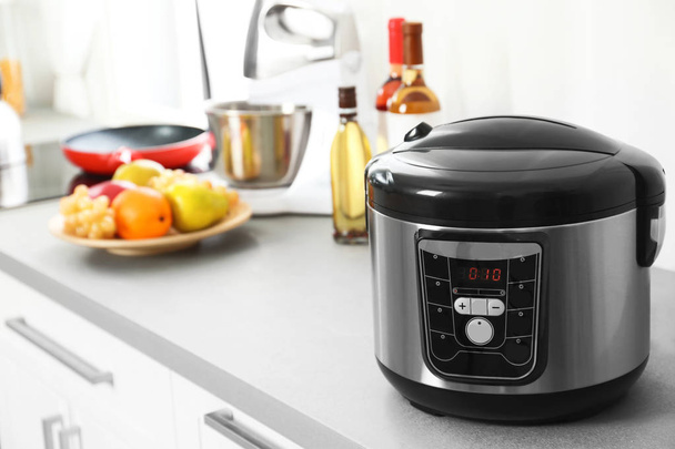 Modern multi cooker and products on table in kitchen. Space for text - Photo, Image