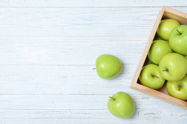 Wooden crate full of fresh green apples on light background, top view. Space for text - Foto, Imagen