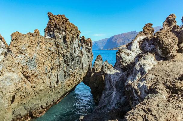 Steile hoge lava rots klippen. Blauwe zee horizon, natuurlijke hemel achtergrond. - Foto, afbeelding