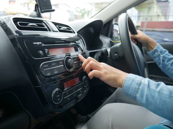 Bouton de presse de main de conducteur femelle sur la radio de voiture
 - Photo, image
