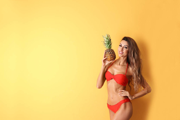 Pretty sexy woman in stylish bikini with pineapple on color background, space for text - Foto, imagen