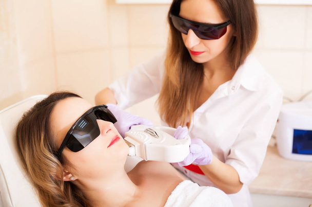 Cuidado com a pele. Mulher recebendo tratamento de depilação a laser em seu rosto
 - Foto, Imagem