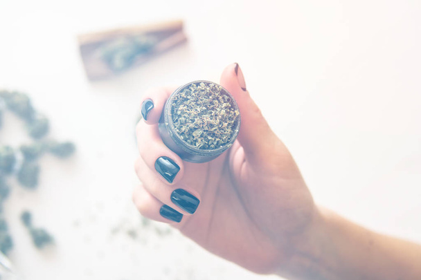 Woman preparing and rolling marijuana cannabis joint. marijuana use concept. Close up of marijuana blunt with grinder. Woman rolling a cannabis blunt on white background. Color toning - Photo, Image